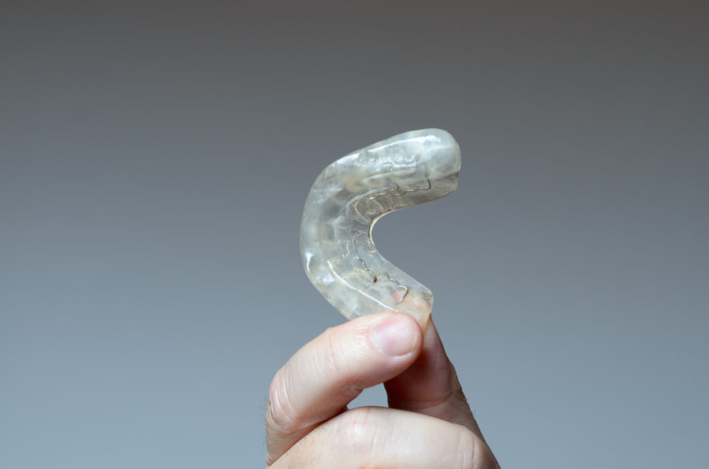 Closeup of hand holding an oral device that can help alleviate symptoms of sleep apnea. 