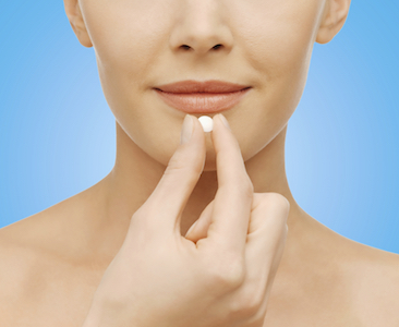 Woman holding a pill which is a common and common form of sedation dentistry found at Southridge Dental in Surrey, BC, Canada.